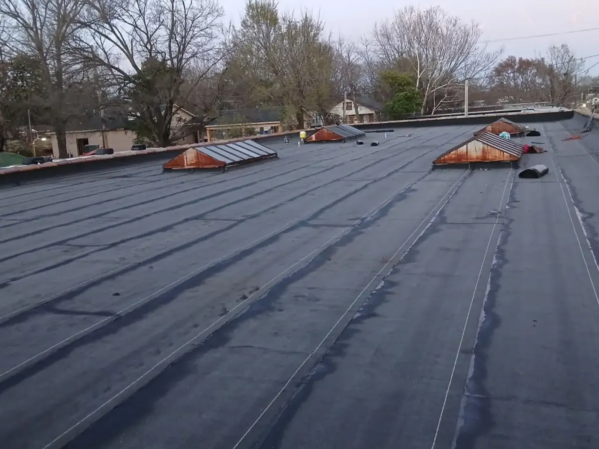 Finished commercial flat roof with new rolled roofing laid around the skylights