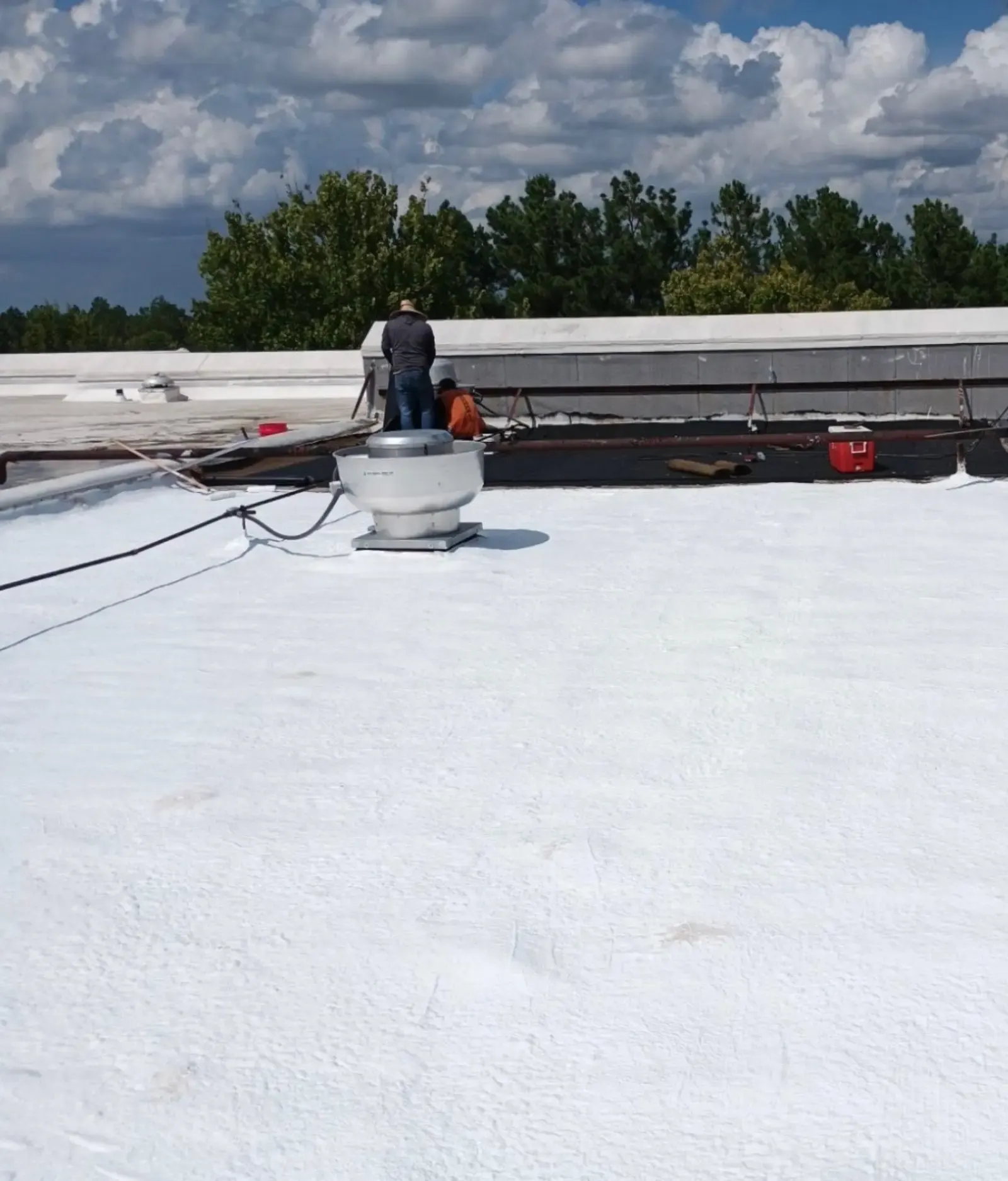 Bohon Roofing crew finishing a white coating on a commercial flat roof