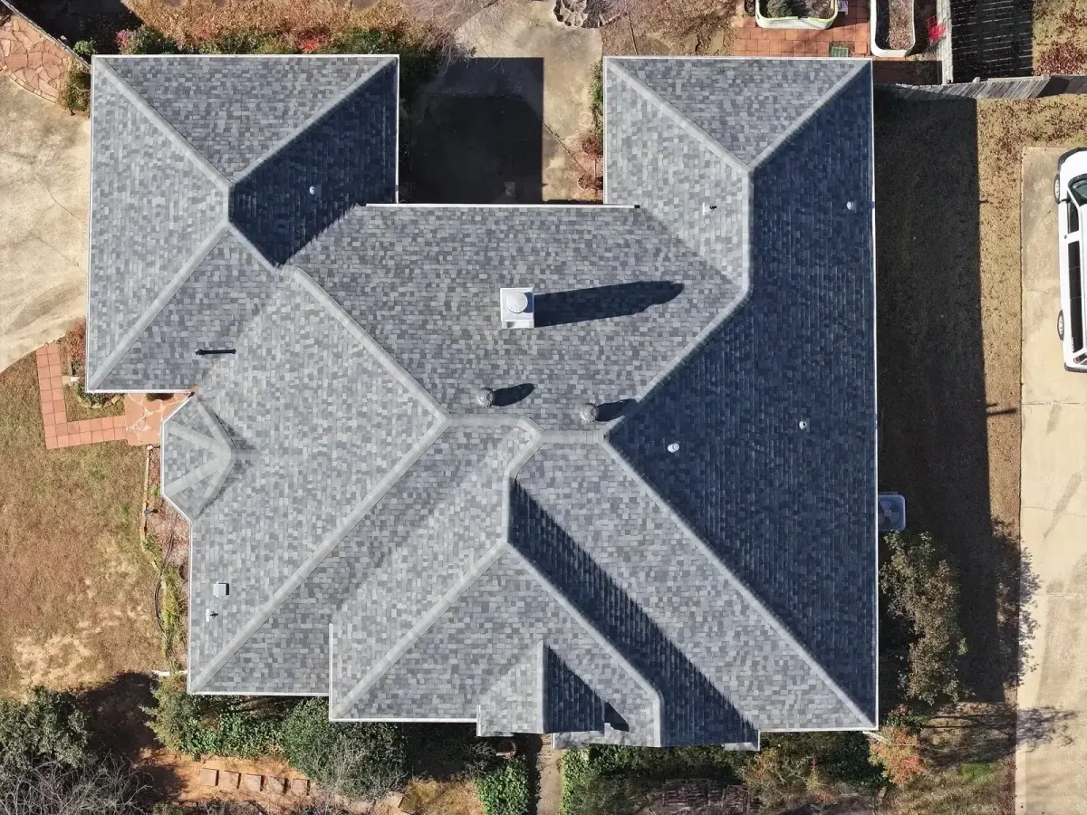 Top-down drone view of a completed hip roof replacement in gray architectural shingles