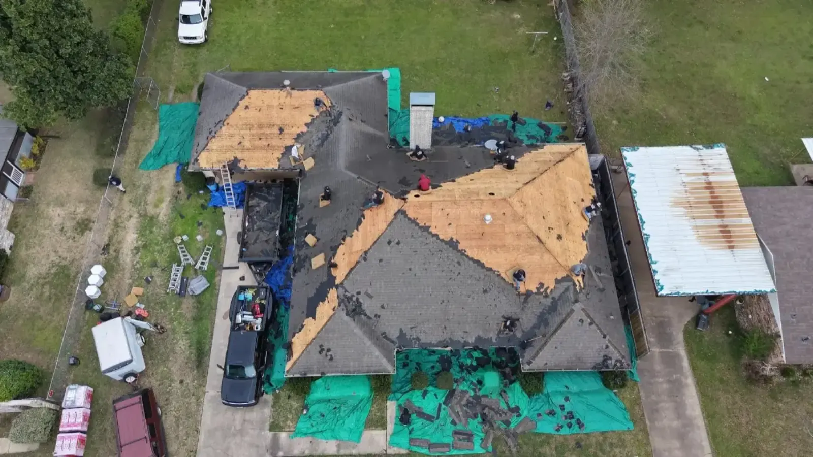 Bohon crew tearing off an old shingle roof with tarps protecting the yard