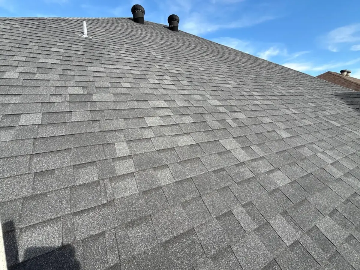 Close-up of freshly installed charcoal architectural shingles with turbine vents